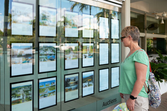 Woman looking at properties for sale in Real Estate window