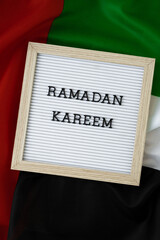 Congratulations with text RAMADAN KAREEM - happy holidays waving UAE flag on background concept. Commemoration Day Muslim Greeting card advertisement. Blessed holy month holiday