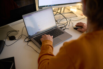 Woman working at home using multi screen set up on desk