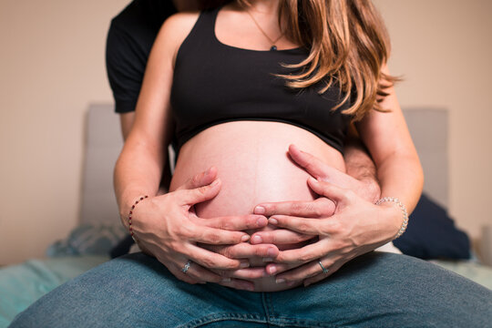 Pregnant couple hands embracing belly