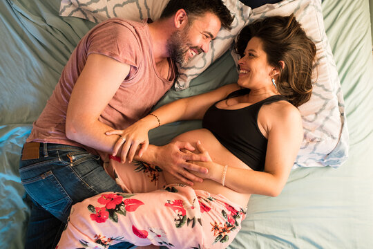 Happy couple enjoying pregnancy on bed 