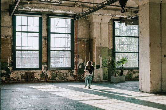 Woman standing in sunlight from big window in the renovated factory