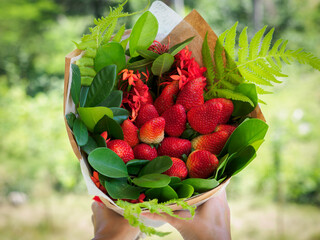 Woman holding a big bouquet of strawberry.