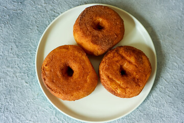Sweet donuts with chocolate powder on a plate, close up