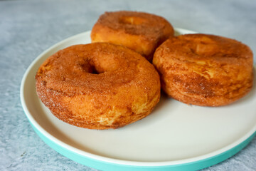 Sweet donuts with chocolate powder on a plate, close up