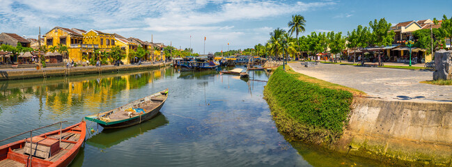Boats on a river through an historic Asian town at Hoi An in Vietnam - obrazy, fototapety, plakaty