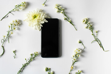a cellphone surrounded by white flowers on white paper