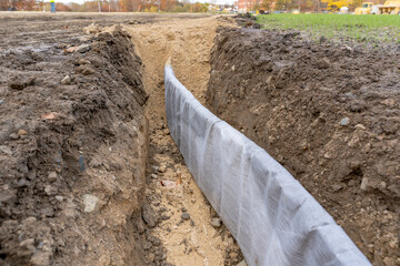 Construction photo of natural turf athletic field vertical edge drain profile, drainage panel...
