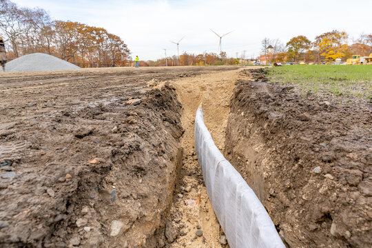 Construction photo of natural turf athletic field vertical edge drain profile, drainage panel between baseball / softball infield clay and natural grass field.