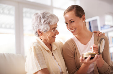 Gift box, necklace and senior mother with woman on sofa for present, giving and surprise in living...