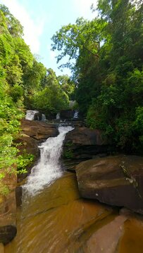 Scenic FPV flight over tropical river and waterfalls among ush jungle in Thailand