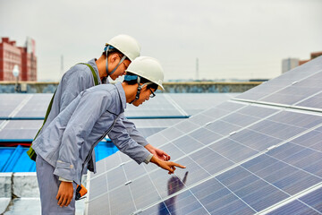Two Asian workers are inspecting solar photovoltaic cells