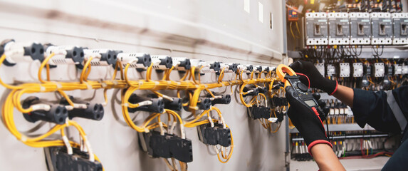 Electricity and electrical safety maintenance service system, Technician hand checking electric current voltage at circuit breaker terminal and cable wiring in main power distribution board. - obrazy, fototapety, plakaty