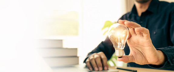 Hand choose light bulb with bright light for creative idea innovation of technology in analyzing...