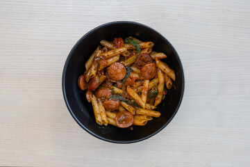 A bowl of penne pasta with chorizo.