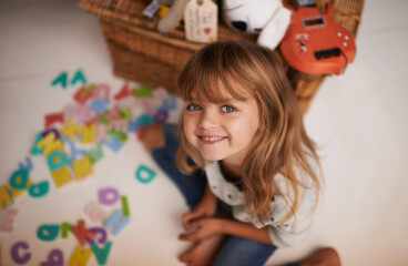 Girl, child and smile with letter toys for learning, development and games in playroom at home. Portrait, education and growth in childhood with alphabet, language and happy kid playing for fun