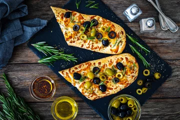 Gordijnen Focaccia alle olive - baked sandwich with green and black olives and rosemary on wooden background  © Jacek Chabraszewski
