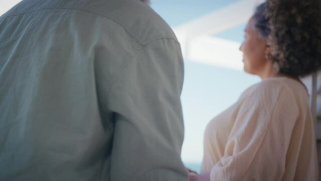 Mature couple on holiday in beach front property overlooking ocean with man kneeling and proposing marriage to woman with ring which she accepts - shot in slow motion