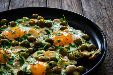 Shakshuka - fried eggs with vegetables on wooden table
