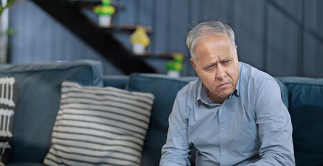 Asian India retired old elder gen x tired upset sad man sitting alone sofa couch feel bad indoor home Indian aged older adult tense lost male think lonely suffer ill sick health issue house - obrazy, fototapety, plakaty