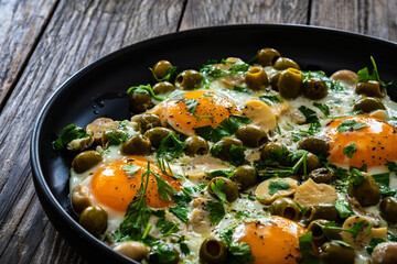 Shakshuka - fried eggs with vegetables on wooden table
