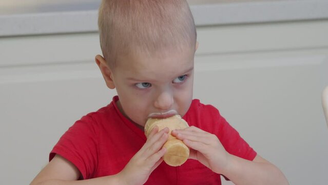 3-year-old child licking ice cream in a waffle cup at home