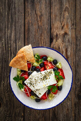 Greek style salad - fresh vegetables with feta cheese nad pita bread on wooden table
