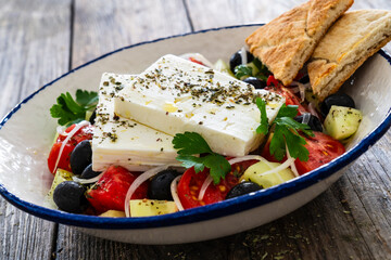 Greek style salad - fresh vegetables with feta cheese nad pita bread on wooden table
