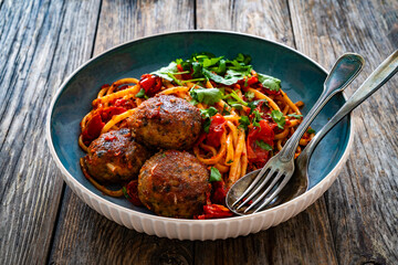 Spaghetti meatballs in tomato sauce on wooden table
