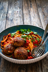 Spaghetti meatballs in tomato sauce on wooden table
