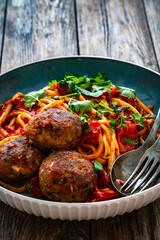 Spaghetti meatballs in tomato sauce on wooden table
