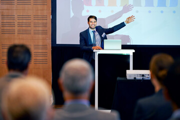 Business man, podium and presentation, pointing at projector screen at conference or workshop with laptop for PPT. Corporate training, seminar and speaker with info, audience and professional speech