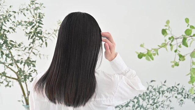  young woman's hair fluttering beauty with organic and natural image of greenery no-face back view to hair care image