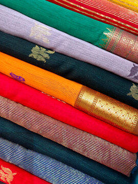 Closeup view of stacked saris or sarees in display of retail shop, for use as indian textiles background.