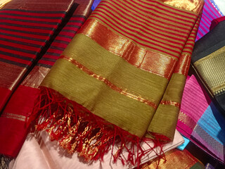 Closeup view of stacked saris or sarees in display of retail shop, for use as indian textiles background.