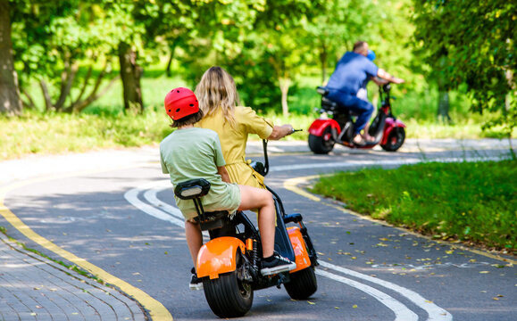 Mother and daughter olls on an electric scooter in the Park
