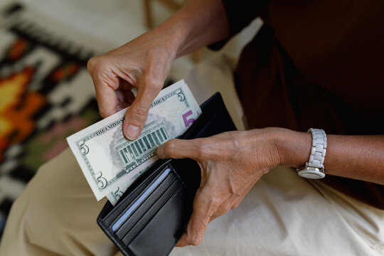 An anonymous woman holding a wallet and money
