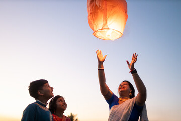 Family releasing sky lantern at twilight