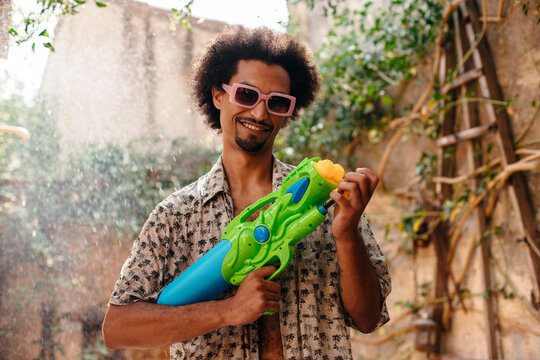 Young man playing with water gun