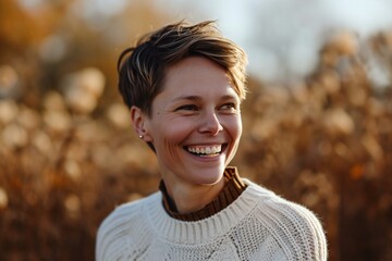 Portrait of a smiling young woman in a white sweater on a background of autumn field