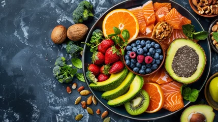 Foto op Canvas A well-arranged platter contains slices of fresh salmon, and vibrant mixed fruits including oranges, strawberries, and blueberries, alongside slices of avocado and a scattering of almonds and walnut © TKL