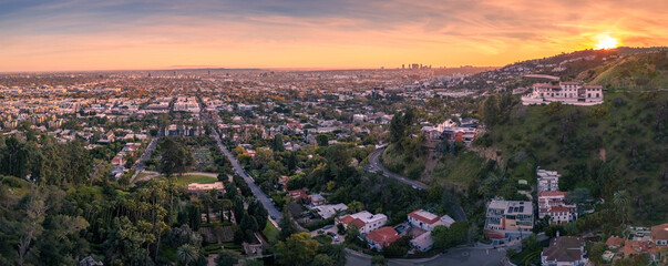 Aerial panorama of residential homes above city of Los Angeles cityscape shot from lush hiking trail in Hollywood Hills at sunset. - 759503163