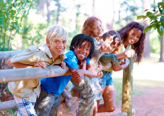 Smile, portrait and diversity on bridge with kids in nature for summer camping in forest, vacation...