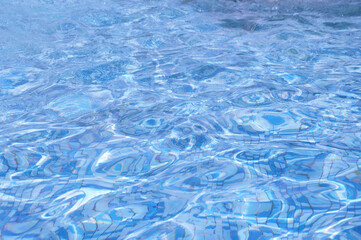 Blue water in the pool under the sun. Abstract background of water reflections on the surface.