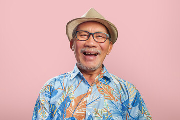 Portrait of Happy Asian Chinese senior man wearing T-shirt laughing over pink isolated background....