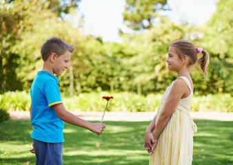 Boy, girl and flower present or outdoor connection with love kindness for young friendship, bonding or innocent. Children, smile and backyard garden for giving gift for summer holiday, play or park