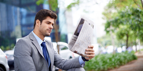 Professional, businessman and reading newspaper in city for information, daily news and updates on local events. Outdoors, male person and serious with article for stories, journalism and newsletter