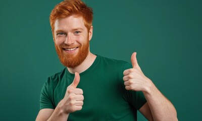 A man with red hair is smiling and giving a thumbs up. He is wearing a green shirt