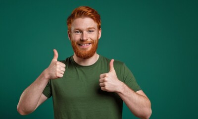 A man with red hair is smiling and giving a thumbs up. He is wearing a green shirt