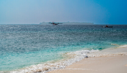 Nice sea coast with a sandy beach and a seaplane on the surface.